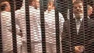 The ousted president of Egypt (in dark jacket), Mohammed Morsi, in court for a hearing, 4 November 2013