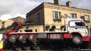A lorry rests on the walls of the Lamb and Lion pub in Bath