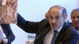 Amhad al-Jarba, the head of Syria's Western-backed National Coalition, holds up an image of alleged torture victims, during the Syria peace talks in Montreux, Switzerland.
