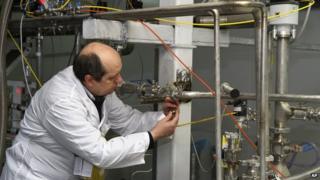 An unidentified International Atomic Energy Agency (IAEA) inspector cuts the connections between the twin cascades for 20 percent uranium enrichment at the Natanz facility (20 Jan. 2014)
