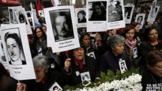 Demonstrators hold up images of their relatives, who were victims of human rights abuse during the former General Augusto Pinochet years, in front of the "La Moneda" Presidential Palace during a rally in Santiago September 11, 2013.