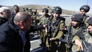 A Palestinian man confronts Israeli soldiers next to the Palestinian village of Ein Sariya after the shooting of Mohammed Mubarak (29 January 2014)