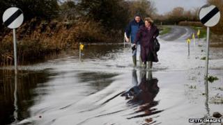 Two people wade through flood waters at Burrow Bridge