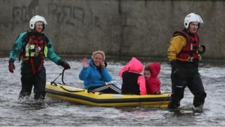 Residents use a boat to navigate flood waters after a flash flood on the Lee Estate in Limerick City