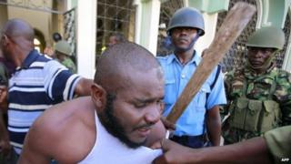 A Muslim man is detained by police officers at the Masjid Mussa Mosque in Kenya"s coastal town of Mombasa February 2, 2014.