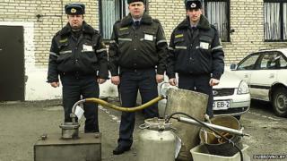 Belarusian police officials display seized distilling equipment