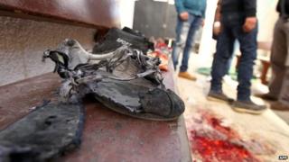 Libyan youths stand next to blood stains and torn shoes at the scene of a blast at a primary school in the Libyan city of Benghazi - 5 February 2014