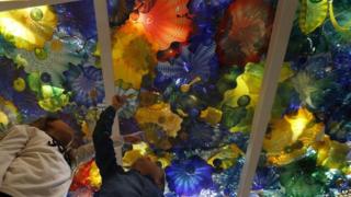 Two children pose underneath a glass sculpture by US artist Dale Chihuly at the Halcyon Gallery in London