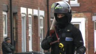 A police officer carries away a battering ram