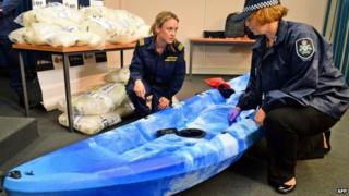A customs officer (C) and a police officer (R) inspect one of the 27 kayaks seized after Australian authorities found A$180m of methamphetamine stashed in kayaks from China in Sydney on 12 February 2014