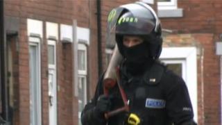 A police officer carries away a battering ram