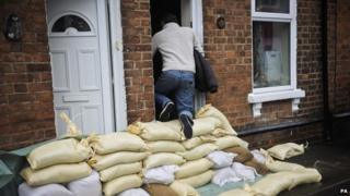 A local resident climbs over sandbags protecting houses on Alney Terrace, Gloucester.