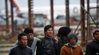 A Nepalese man consoles a relative, center, of a missing passenger