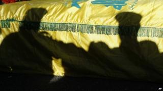 The shadow of Hezbollah fighters are silhouetted on the coffin of their commander Ali Bazzi, who was killed in Syria during a battle against rebels, during his funeral procession, in the southern port city of Sidon, Lebanon, on 9 December 2013.