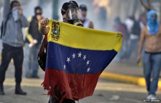 An anti-government protestor in Venezuela holding up a battered flag