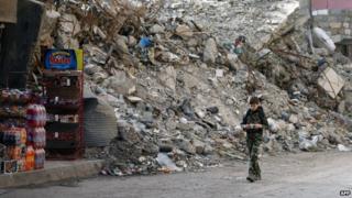 Boy walks past destroyed building in Deir Ez-Zor