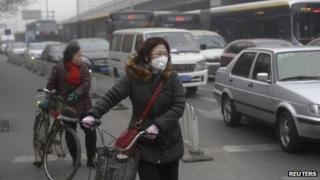 A cyclist wears an anti-pollution mask at a traffic junction on a busy street amid thick haze in Beijing on Tuesday