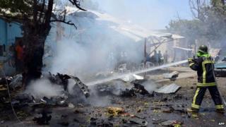 A fire-fighter hoses down the wreckage at the site where a car bomb exploded in the Somali capital Mogadishu on 27 February 2014