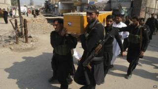 Pakistani security personnel carry the body of a fellow officer who was killed in a bomb blast