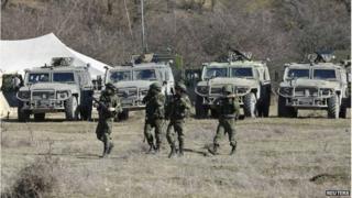 Military personnel, believed to be Russian servicemen, walk near the territory of a Ukrainian military unit in the village of Perevalnoye outside Simferopol, on 3 March
