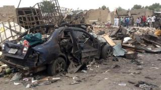People gather on 2 March 2014 near a car which had exploded in the city of Maiduguri in northern Nigeria