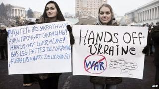 Two women hold banners reading "hands off Ukraine" in different languages, in Kiev's Independence Square