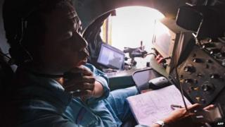 Military personnel scanning the sea aboard a Vietnamese Air Force aircraft taking part in a search mission for a missing Malaysia Airlines aircraft on 8 March 2014