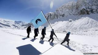 Activists hike through snow with Republica Glaciar flag
