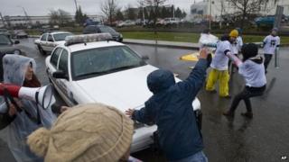 A Tacoma Police Officer uses his vehicle to move Enrique Agular out of the way as protesters block the road in front of the federal Northwest Detention Center 24 February 2014