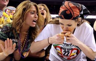 A wingette, left, cheers on contestant Molly Schuyler, of Omaha, Nebraska