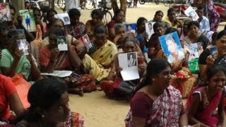 Tamil women hold up pictures of their missing relatives