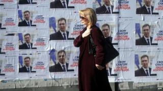 A woman walks past election posters in Belgrade. Photo: 15 March 2014