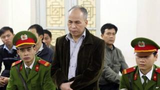Dissident blogger Pham Viet Dao, standing at centre, appears at a court in Hanoi, Vietnam Wednesday, 19 March 2014