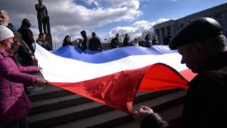 Demonstrators hold a Russian flag in the Crimean city of Simferopol on 18 March, 2014.