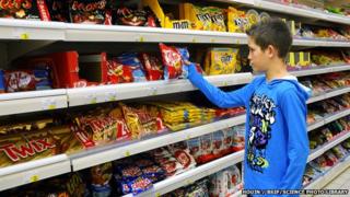 Boy being tempted by chocolates in a supermarket