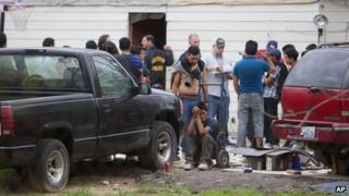 People wait outside a suspected stash house in southeast Houston on 19 March 2014