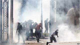 Egyptian Muslim Brotherhood students and supporters of ousted president Mohamed Morsi run through smoke during clashes with riot police following a demonstration outside Cairo University on March 26, 2014