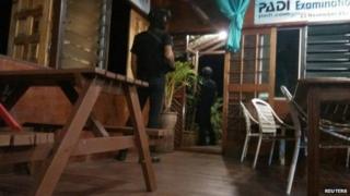 Armed men are seen near a door of Singamata Reef Resort hotel in Sabah on 2 April, 2014