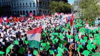 People hold coloured papers to create a giant Hungarian tricolor as sympathisers and party members of the opposition party attend in front of the building of the Hungarian State Opera in Budapest