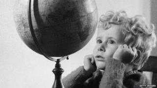 A 1950 photo of a boy looking at a globe.