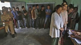 People stand in line to cast their votes inside a polling booth at Senapati, in Manipur state, India, , April 9, 2014