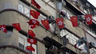 Chinese and Hong Kong national flags hang before residential buildings in Hong Kong on 4 January 2014