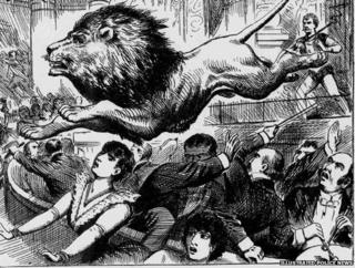 A lion leaps over members of an audience