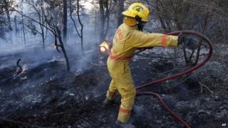 A fire fighter moves a hose while battling a fire in Logan County, Oklahoma, on 4 May 2014