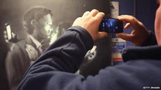A mobile phone is used to take a picture of Banksy's Mobile Lovers artwork