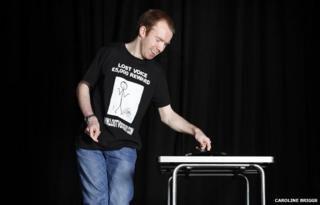 Lee Ridley onstage using his automated-speaking device