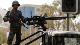 A soldier stands guard on a military vehicle at a checkpoint on a road to the city of Sanaa, May 11