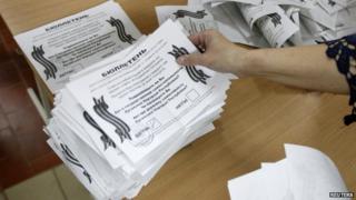 Member of local election commission sorts ballot after ballots were taken from ballot box as commission start counting votes of referendum on status of Luhansk