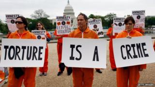 Activists from Amnesty International protest holding signs 'torture is a crime'
