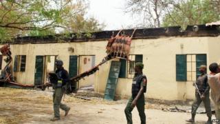 Nigerian policemen walk past Government Girls Secondary School in Chibok, Borno state (21 April 2014)